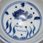 Kleine Ming Dy Schale Blau-Weiss mit Fisch und Wasserpflanzen im Zentrum sowie an der Aussenwandung. Boden unglasiert.
