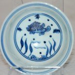 Kleine Ming Dy Schale Blau-Weiss mit Fisch und Wasserpflanzen im Zentrum sowie an der Aussenwandung. Boden unglasiert.