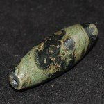 Dzi Perle in grünlichem Stein mit vielen Augen